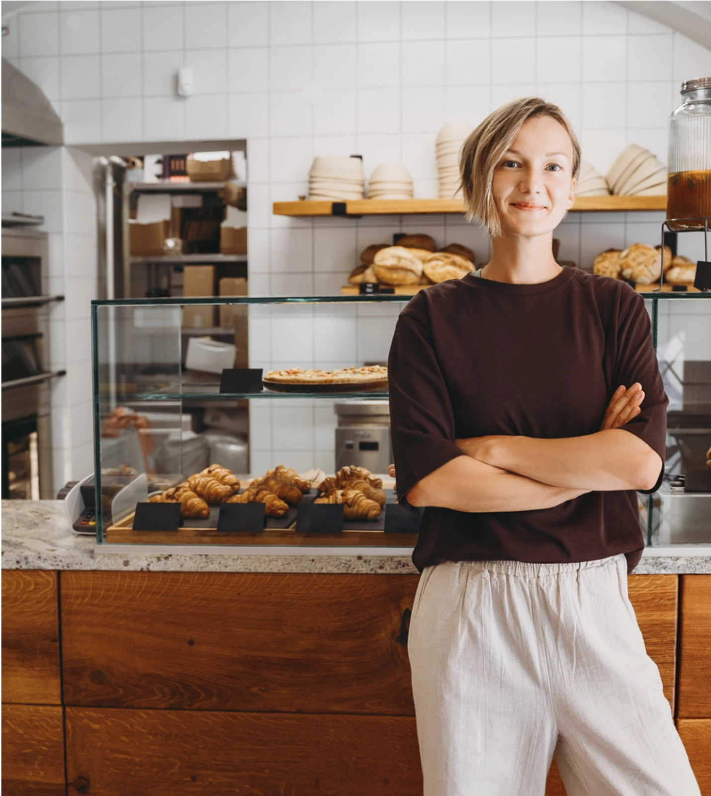 A smiling bakery owner standing in front of a counter with baked goods, representing SMBs using OutThink's Community Edition.